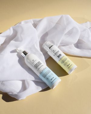 Protectores solares SUNNA de Terranian, cosmética natural, sobre sábana blanca y fondo amarillo